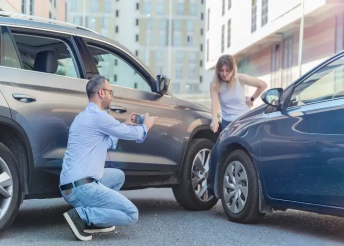 Two people taking pictures after a car accident they were involved in.