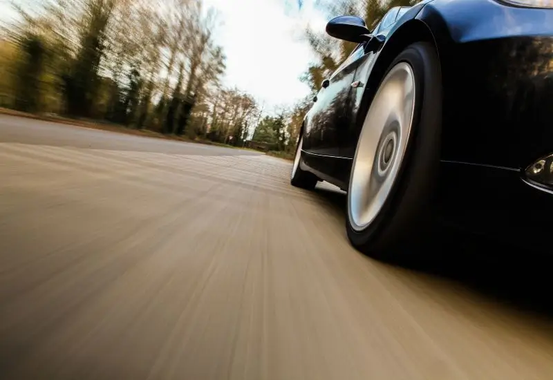 Side view of black car speeding on the road