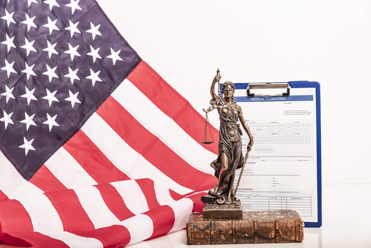 American flag with Lady Justice statue and medical claim form