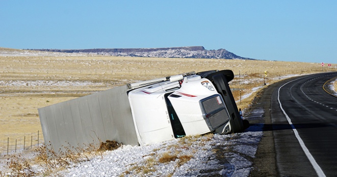 Overturned semi-truck on the side of a rural highway after an accident