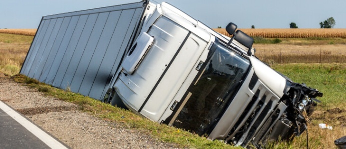 Overturned semi-truck lying in a ditch beside a highway after a crash