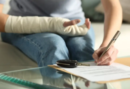Person with bandaged arm signing documents at a table inside a Houston, TX home