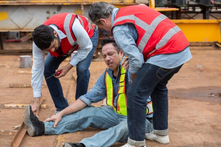 Construction site scene with coworkers assisting an injured worker in Houston, TX