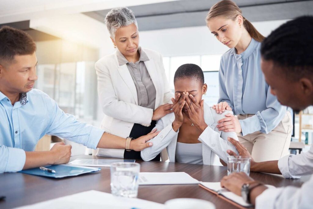 Group of people supporting individual during emotional distress claim meeting at office table with legal discussion in Bellaire, TX